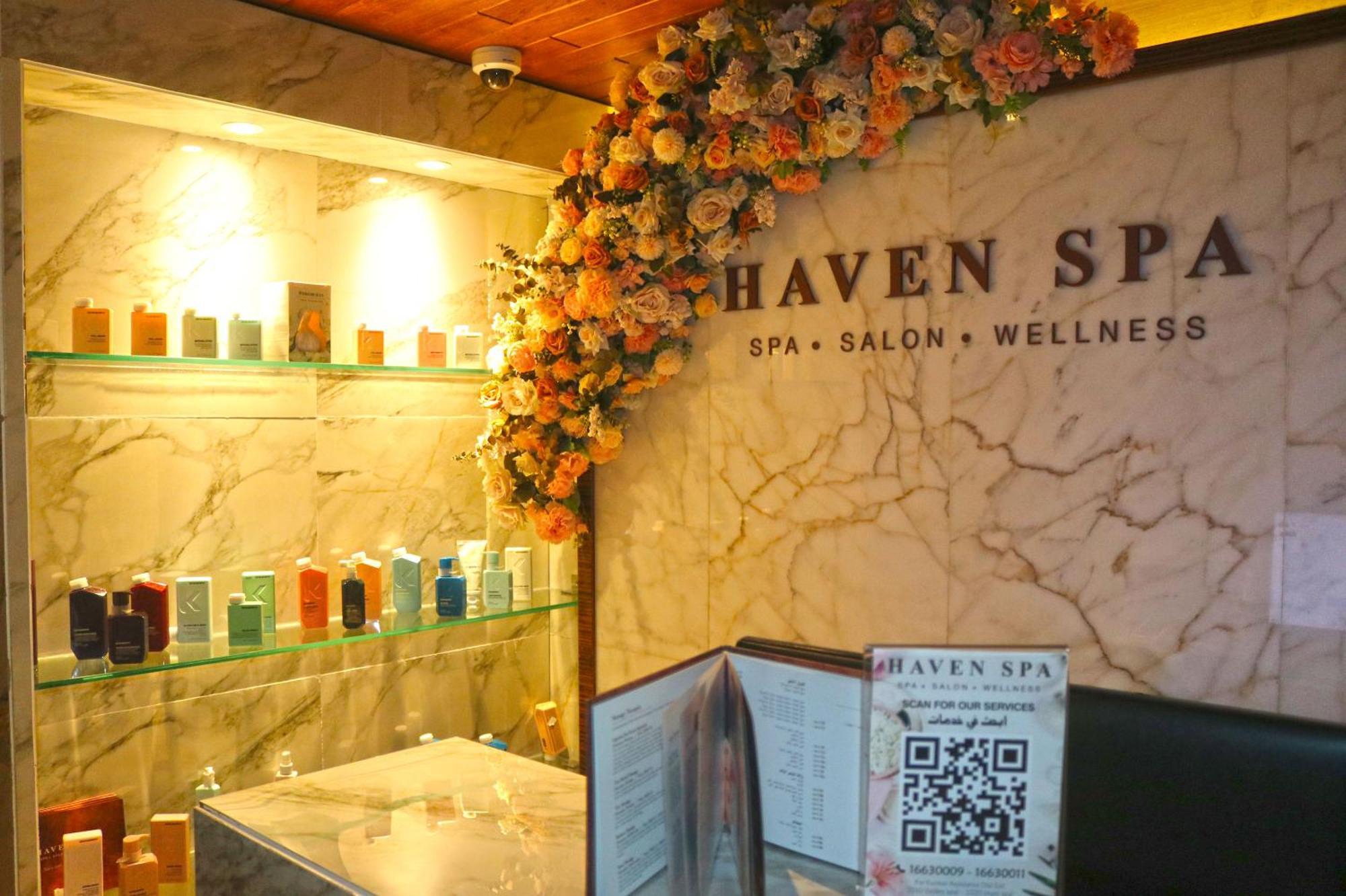 Lagoona Beach Luxury Resort And Spa Μανάμα Εξωτερικό φωτογραφία The photo shows the interior of a spa called "Haven Spa." The wall is decorated with beautiful artificial flowers, creating an inviting atmosphere. There are several shelves displaying various colorful bottles and products, likely for skincare or wel