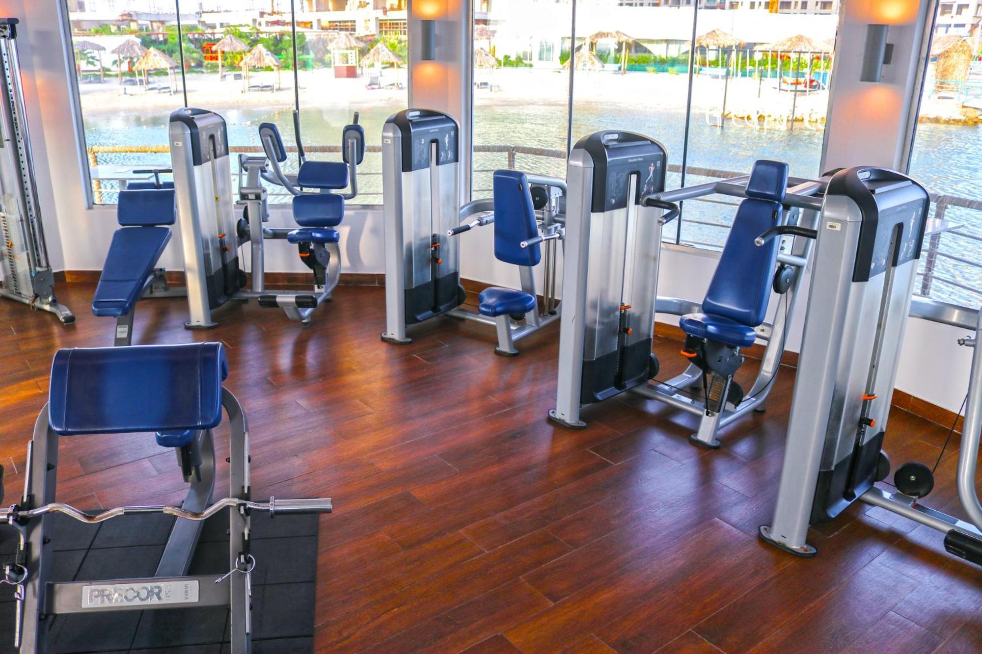 Lagoona Beach Luxury Resort And Spa Μανάμα Εξωτερικό φωτογραφία The photo shows a gym or fitness center with several pieces of exercise equipment. There are multiple machines designed for strength training, including seated machines with padded seats and backrests. The equipment appears to have a modern design an