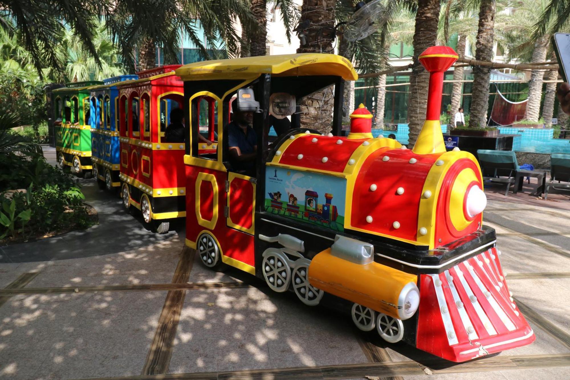 Lagoona Beach Luxury Resort And Spa Μανάμα Εξωτερικό φωτογραφία The photo shows a colorful miniature train. It features a vibrant design with bright red, yellow, and blue colors. The front of the train resembles a classic steam engine, complete with a prominent smokestack. The train is designed to resemble a fun 