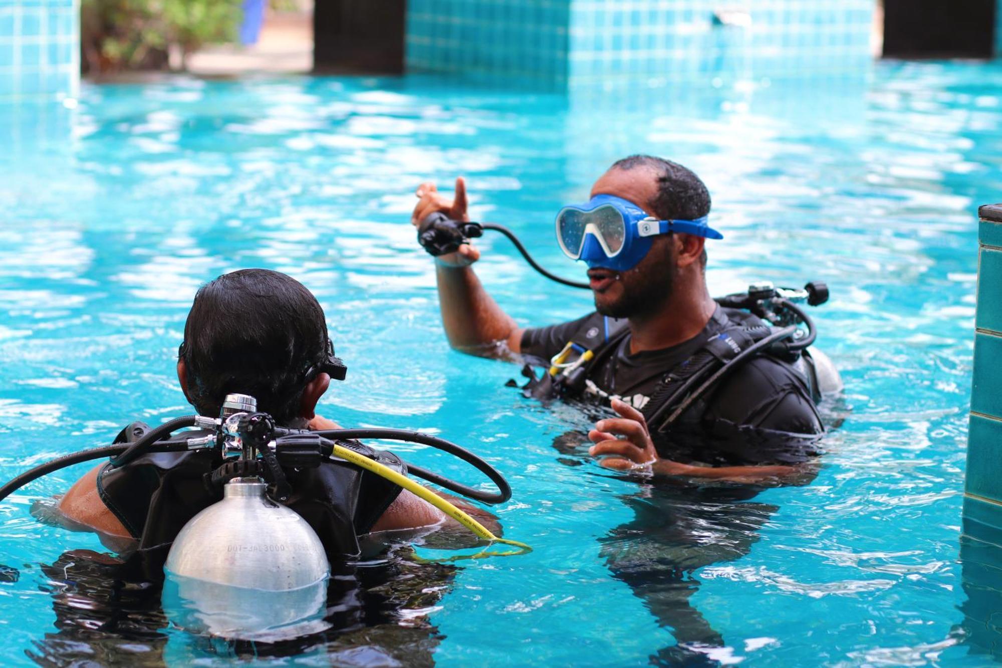 Lagoona Beach Luxury Resort And Spa Μανάμα Εξωτερικό φωτογραφία The photo shows two divers in a pool. One diver is wearing a scuba mask and is speaking to the other diver, who is also equipped with scuba gear. They appear to be engaged in a discussion, possibly related to diving instructions or safety. The water 