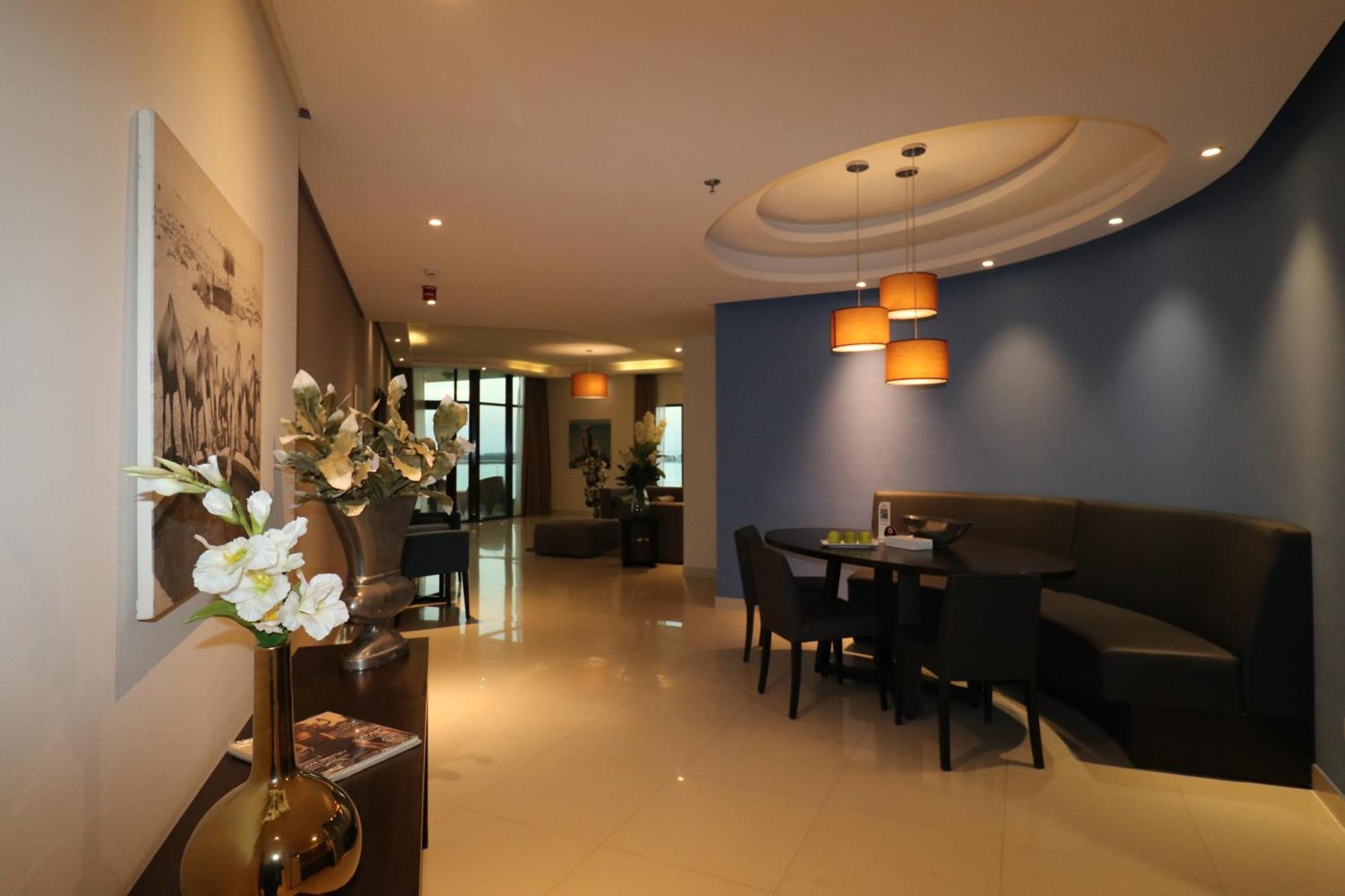 Lagoona Beach Luxury Resort And Spa Μανάμα Εξωτερικό φωτογραφία The photo showcases an interior space, likely a modern lounge or reception area. It features a combination of soft lighting, neutral-colored walls, and decorative elements. There are elegant light fixtures hanging from the ceiling, and a curved blue 